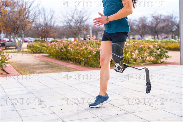 Side view of the lower part of a disabled person with prosthetic leg running in an urban park