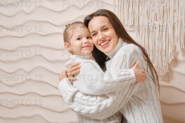 Concept of soft and warm family relationships. Lovely mother embracing her little daughter