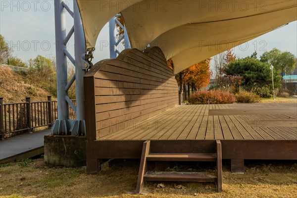 Side view of wooden outdoor stage with white canvas awning in public park