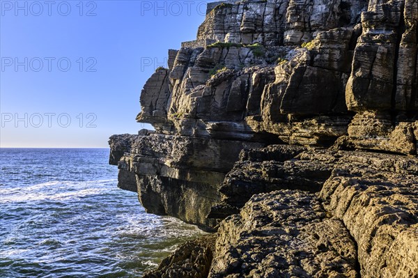 Beautiful cliffs and rock formations in Peniche, Portugal, on sunny day. Weathered rock formations, geological interest, cliffs, blue sea waves, tide, coastline, clear blue sky, Europe