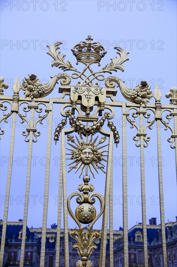 Emblem of the Sun King with Apollo's head, sunbeams and sceptre with French lily on the royal grille, Chateau de Versailles, Yvelines department, Ile-de-France region, France, Europe