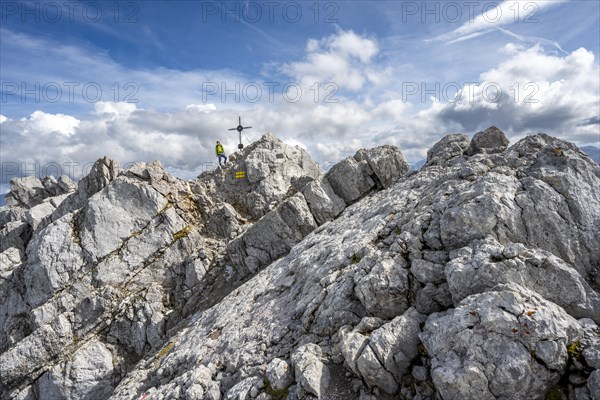 Mountaineer on the rocky summit of the Watzmann Mittelspitze with summit cross, Watzmann crossing, Berchtesgaden National Park, Berchtesgaden Alps, Bavaria, Germany, Europe