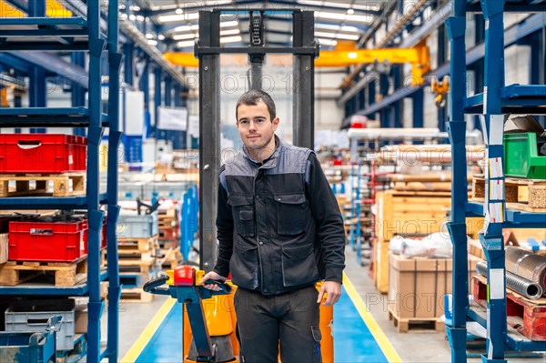 Frontal view of a male worker walking among shelves with handcart in a warehouse