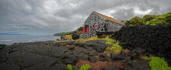 Traditional stone house on the coast with a view of the sea and cloudy sky, North Coast, Santa Luzia, Pico, Azores, Portugal, Europe