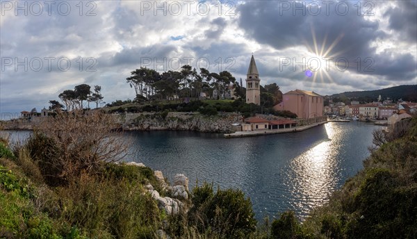 Morning sun breaking through clouds, view of the harbour entrance of Veli Losinj, with Antonius church, panoramic view, island of Losinj, Kvarner Gulf Bay, Adriatic Sea, Croatia, Europe