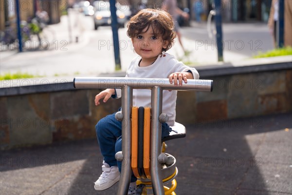 Portrait of a cute girl in an urban playground sitting on a bike figure