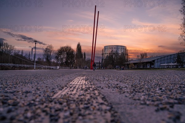 Perspective of a street leading to a sculpture under a colourful evening sky, Enzauen Park, Gasometer, Pforzheim, Germany, Europe