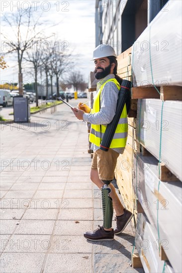 Vertical side view portrait of an engineer with prosthetic leg working in a construction site outdoors