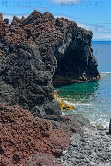 Rugged coastline with steep volcanic cliffs jutting out into the deep blue sea, lava rocks Coastal hiking trail Ponta da Iiha, Manhenha, west coast, Pico, Azores