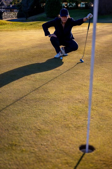 Female Golfer Concentration on the Putting Green on Golf Course with Sunlight in Switzerland