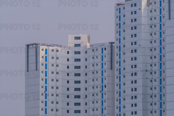New highrise apartments with unfinished white concrete exterior walls and blue coverings on widow frames in the Shintanjin area of Daejeon, South Korea, Asia