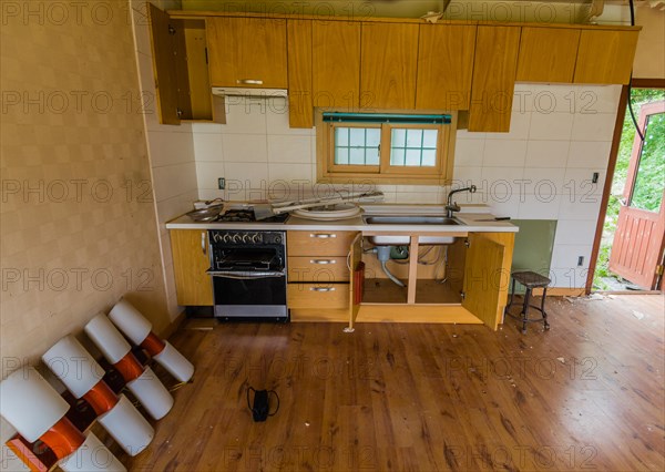 Kitchen area of abandoned house with dirt and electrical fixtures debris on counter top and leaning against wall