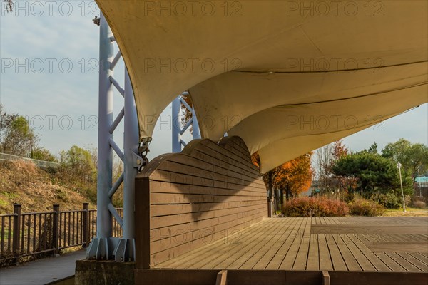 Closeup side view of wooden outdoor stage with white canvas awning in public park