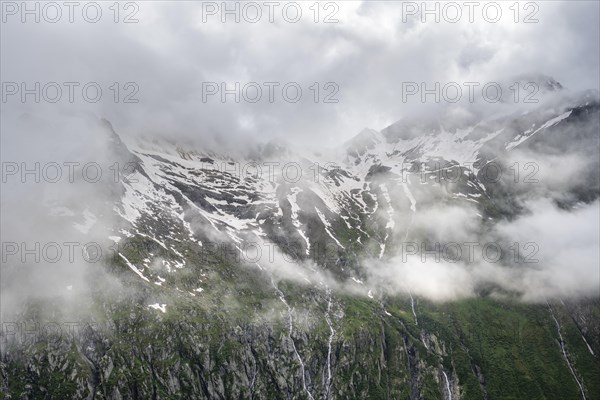 Snow-covered cloudy mountains with summit Hochsteller, mountain streams as waterfalls on a mountainside, Furtschaglhaus, Berliner Hoehenweg, Zillertal, Tyrol, Austria, Europe