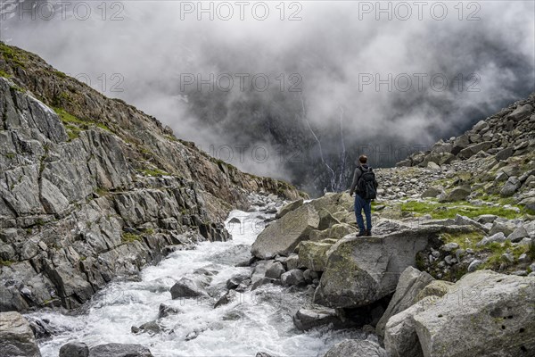 Mountaineer at a mountain stream, Furtschaglbach, cloudy mountains in the background, Furtschaglhaus, Berliner Hoehenweg, Zillertal, Tyrol, Austria, Europe