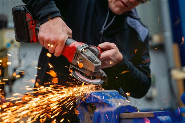 Close-up of a worker using an electric wheel grinding in a factory