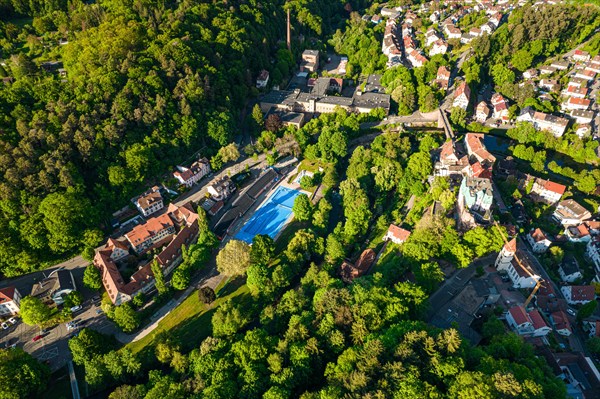 Aerial view of an outdoor swimming pool surrounded by trees and the shadows cast by the low sun, Pforzheim, Germany, Europe