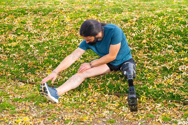 Elevated view of a motivated amputee athlete stretching before running in a park