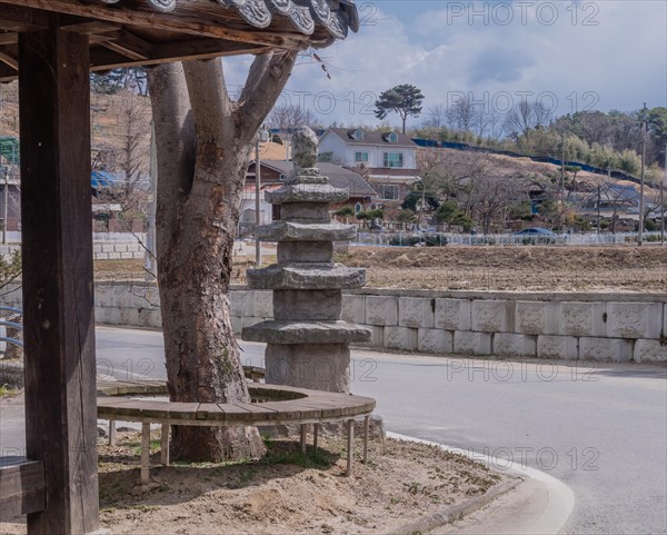 Five story concrete pagoda next to tree in public park on corner of rural street