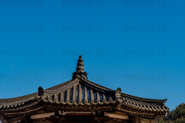 Tiled rooftop of oriental gazebo against clear blue sky