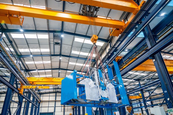 Low angle view photo of a huge crane lifting heavy machinery indoors