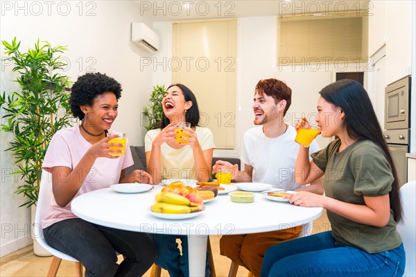 Young multi-ethnic group of friends laughing while eating healthy breakfast at home