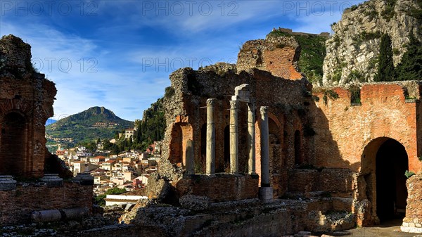 Ancient amphitheatre, ancient columns and ruins overlooking a town and surrounding mountains, Taormina, Eastern Sicily, Sicily, Italy, Europe