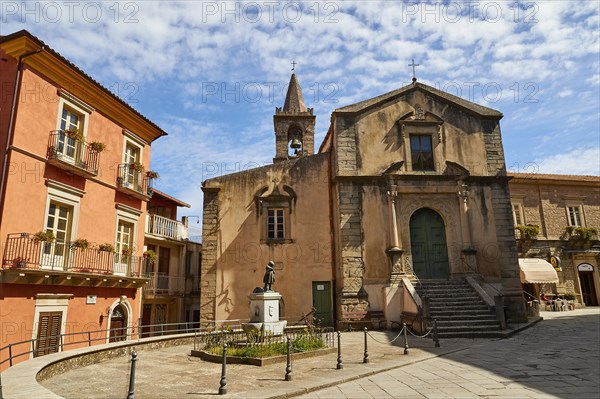 A small square with an old church and statues under a blue sky in a town, Novara di Sicilia, Sicily, Italy, Europe