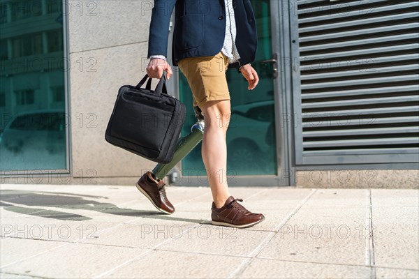 Lower part of an unrecognizable man with shorts and prosthetic leg walking along a financial district