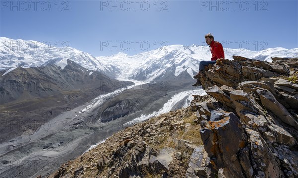 Mountaineer at Traveller's Pass with view of impressive mountain landscape, high mountain landscape with glacier moraines and glacier tongues, glaciated and snow-covered mountain peaks, Lenin Peak and Peak of the XIX Party Congress of the CPSU, Trans Alay Mountains, Pamir Mountains, Osh Province, Kyrgyzstan, Asia