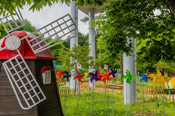 Miniature windmill in front of colorful pinwheels at roadside park