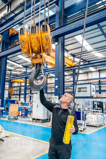 Vertical photo of a male operator using an industrial crane in a logistics factory
