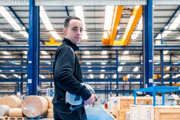 Worker turning to smile at camera standing proud in a logistic center