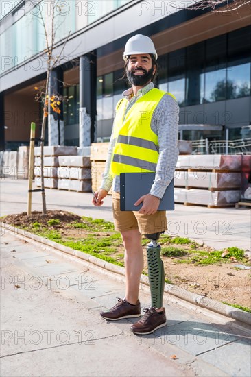 Vertical portrait of an employee with prosthetic leg working on construction site wearing protective equipment