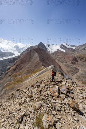 Mountaineer at Traveller's Pass with view of impressive mountain landscape, high mountain landscape with glacier moraines and glacier tongues, glaciated and snow-covered mountain peaks, Lenin Peak, Trans Alay Mountains, Pamir Mountains, Osh Province, Kyrgyzstan, Asia