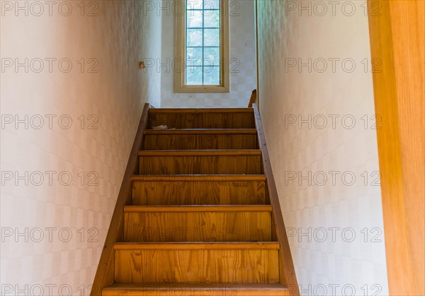 Wooden staircase with window on second floor landing in abandoned house
