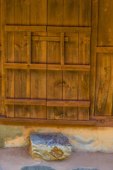 Oriental wooden door that slides to open and close on old stucco building