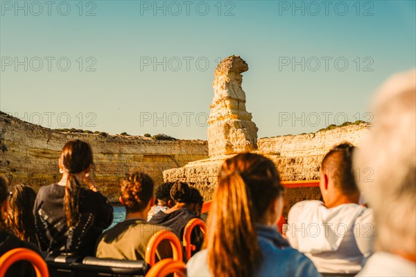 Tourist in the boat admiring rock formation called submarine, Albufeira, Algarve, south of Portugal