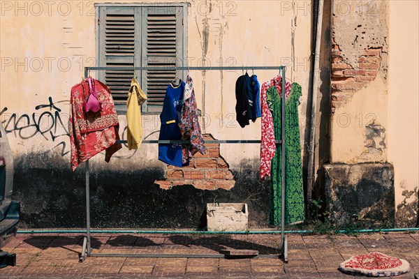 Laundry hung to dry outside in front of a weathered wall on the street side of Kampot Cambodia, showing the candid authentic khmer daily life, culture and lifestyle
