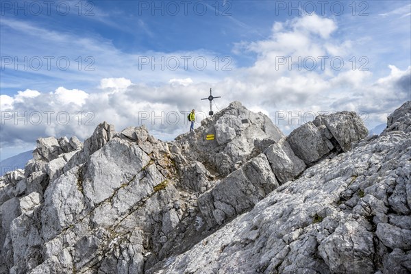 Mountaineer on the rocky summit of the Watzmann Mittelspitze with summit cross, Berchtesgaden National Park, Berchtesgaden Alps, Bavaria, Germany, Europe