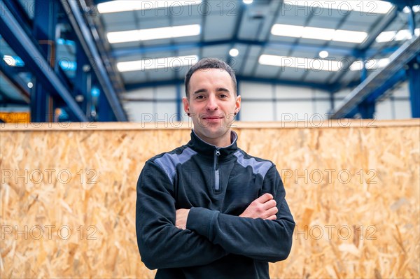 Engineer standing proud with arms crossed smiling at camera in a factory