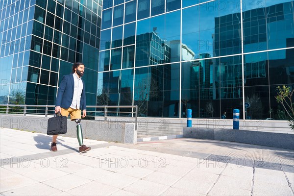 Businessman with prosthetic leg arriving at a financial building carrying laptop bag in the morning