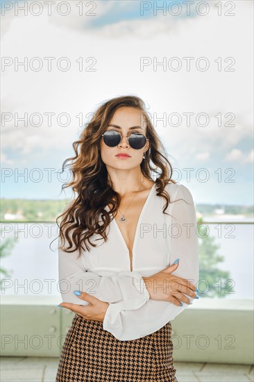 Outdoor portrait of arrogant woman in sunglasses with folded arms