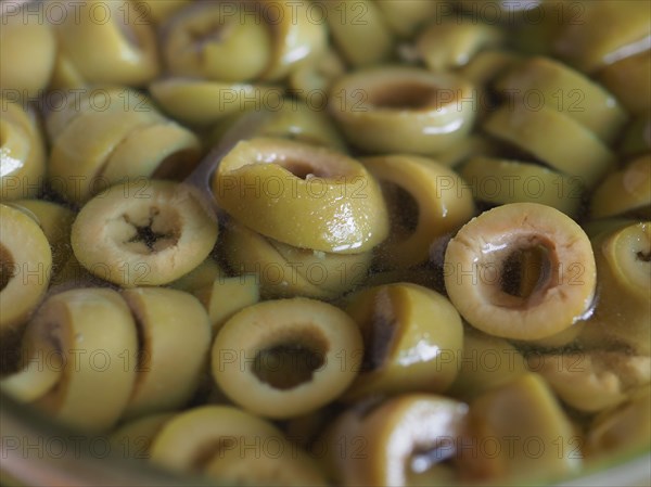 Sliced green olives in brine background