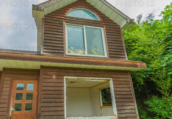 View of window on second story, front door and first floor window frame of abandoned house in countryside