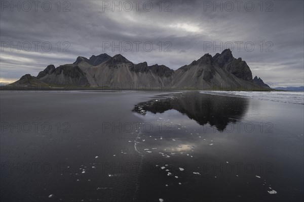 Vestrahorn, mountains with black lava sand, reflection in the water, south coast of Iceland