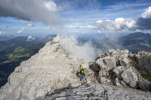 Climber on a via ferrata secured with steel rope, narrow rocky ridge, Watzmann crossing to Watzmann Mittelspitze, view of mountain panorama, Berchtesgaden National Park, Berchtesgaden Alps, Bavaria, Germany, Europe