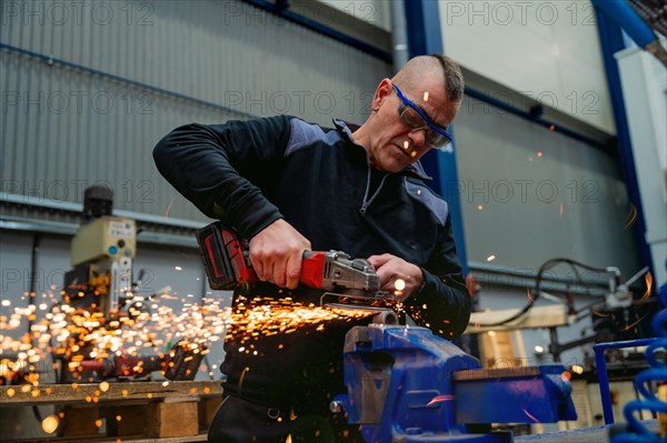 Worker with protective gear using an electric wheel grinding in a factory