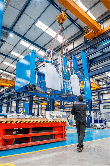 Vertical photo of a worker lifting heavy machinery using a crane