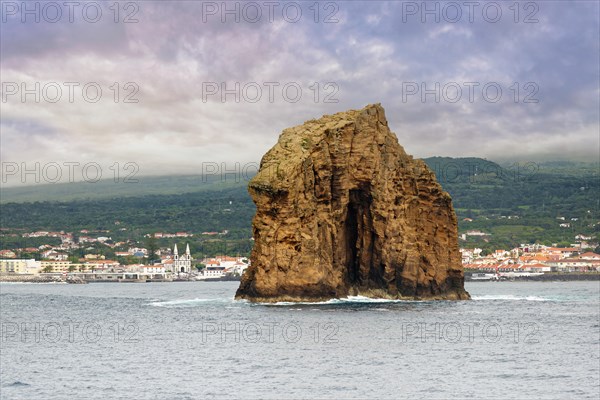 The majestic rock 'Iieu em Pe' rises from the sea, background with Pico Island and the town of Madalena under a cloudy sky, Iieu Deitado, Iieu em Pe, Horta, Faial, Azores, Portugal, Europe